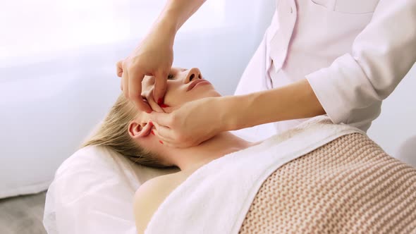 Beautician cosmetologist makes lifting face massage, pinch and roll technique