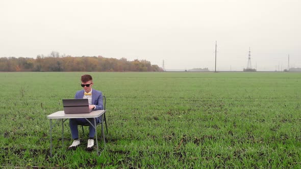 Around Drone Fly View of Young Man Working Remotely with Laptop Outside Alone Isolated on Spring