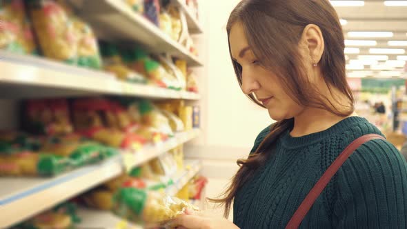 Brunette Woman in Green Sweater Choosing Pasta in Supermarket