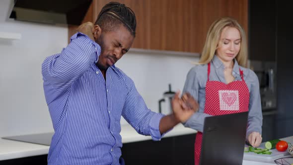 Exhausted Overworked African American Man Stretching Painful Neck As Caucasian Woman in Apron