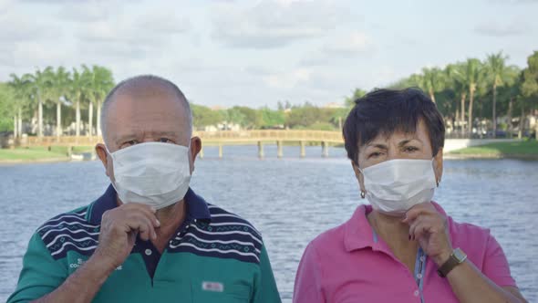 Elderly Couple Looking at Camera While Taking Face Masks Off in Front of Lake