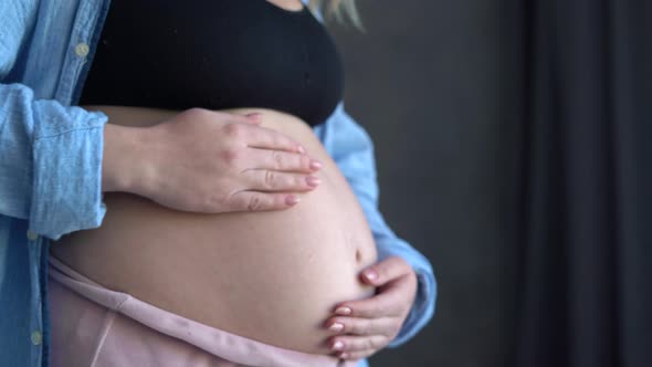 Pregnant Woman Stroking Belly Near Window Indoors Close Up