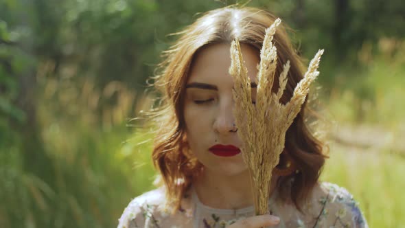 Closeup Portrait of an Attractive Woman with Closed Eyes and a Bouquet of Spikelets in Her Hands