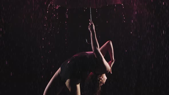 An Acrobatic Dance with an Umbrella in the Rain Performed By a Young Slender Female Gymnast. Shot in