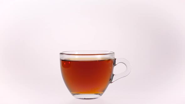 Black Tea Is Poured Into Transparent Cup From Glass Teapot