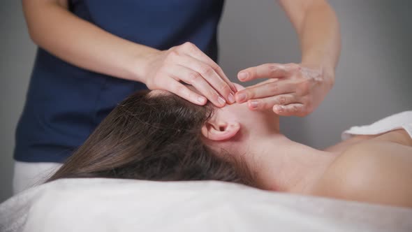 Massage Session  Young Woman Therapist Using Her Fingers on the Face of Her Client