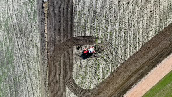 Red tractor plowing field in spring, aerial view, Poland