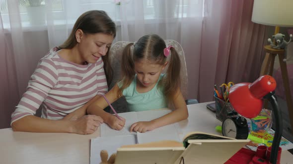 Mother And Daughter Doing Homework From School Together