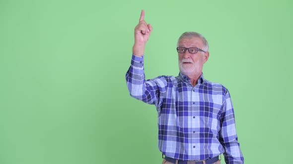 Happy Senior Bearded Hipster Man Pointing Up and Looking Surprised