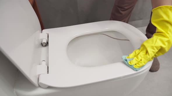 A Housewife in Yellow Rubber Gloves Cleans the Toilet with Chemistry