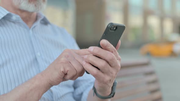 Close Up of Old Man Using Smartphone Outdoor on Bench