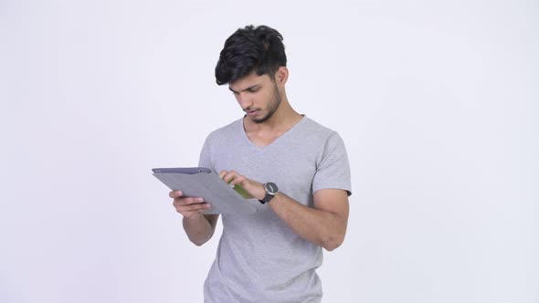 Young Happy Bearded Indian Man Using Digital Tablet and Getting Good News