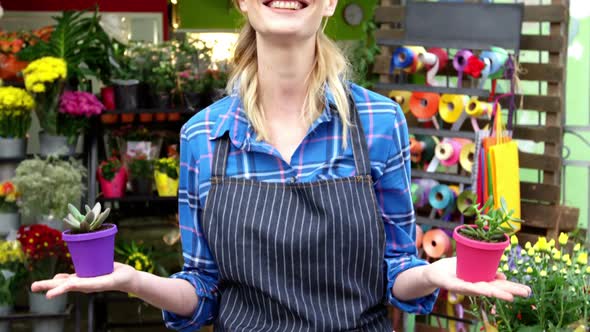 Female florist holding plant pot in flower shop