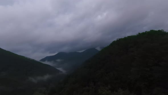 Aerial View Flying Above Lush Green Tropical Rain Forest Mountain with Rain Cloud Cover During the