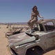 Young Woman in Safari Overalls Sits on the Rooftop of Abandoned Old Rusty Car - VideoHive Item for Sale