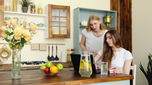 Two Young Women Shopping Online, Choosing And Discussing Goods