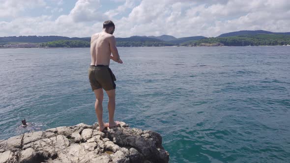 The man running from the rocks is Jumping from the Cliff into the Water. Summer Fun Lifestyle.