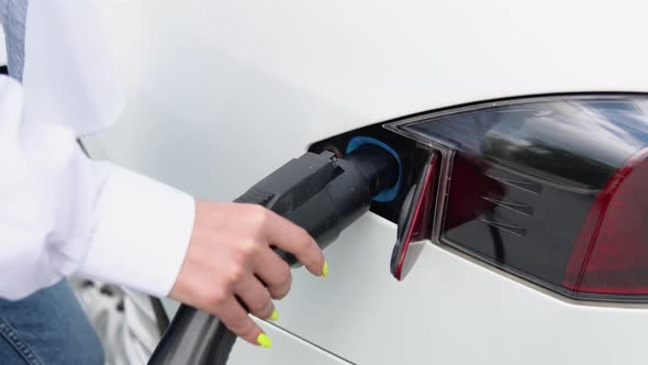 Close Up View of Woman's Hands Plugging Power Supplier to Electric Car