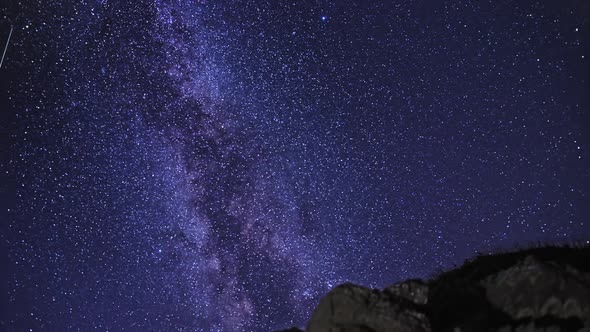 Starry Sky and the Milky Way Galaxy Rotating over Rocks Crest Night Time Lapse