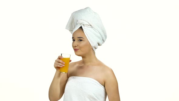 Spa Woman in White Towel on Her Head Drinks Orange Juice From Glass Isolated on White Background