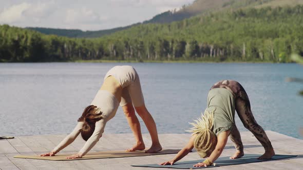 Two Young Women Practicing Vinyasa Yoga in Nature