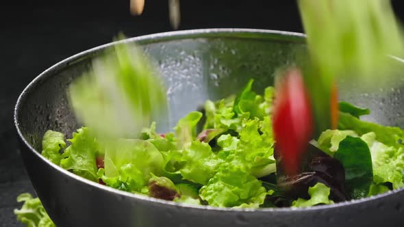 Fresh salad falling in bowl on black background