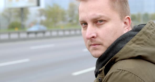 The face of a serious pensive man sitting on the street