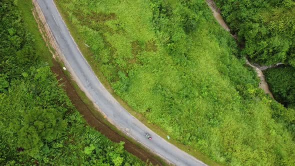 Aerial View of the Crooked Road in The Village People Riding a Motorcycle Around Green Forests and