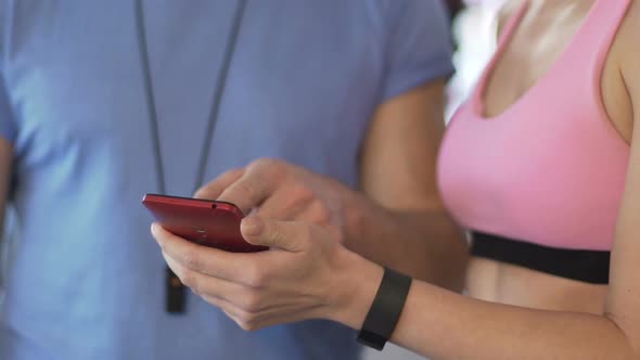 Young Woman Showing Workout Results to Personal Trainer on Mobile Application