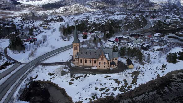 Magnificent aerial orbit of Kabelvag Church in winter with snow covered mountains in the background,