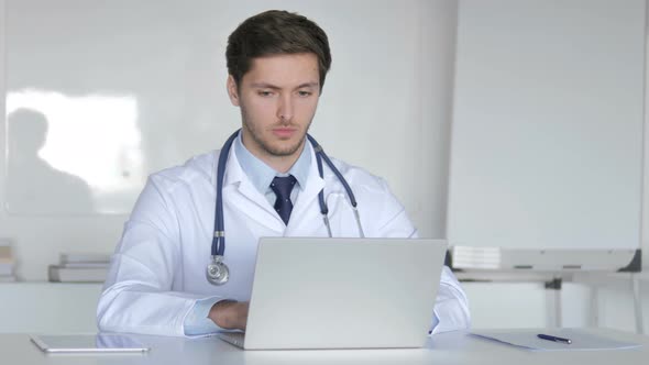 Young Doctor Working On Laptop in Clinic