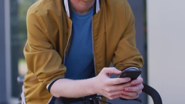 Thoughtful albino african american man with dreadlocks on bike using smartphone