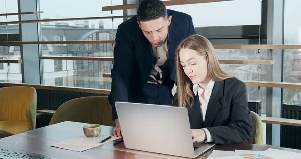 Portrait of a Man and a Woman Discussing Work with Notebook in the Brightly Lit Modern Office