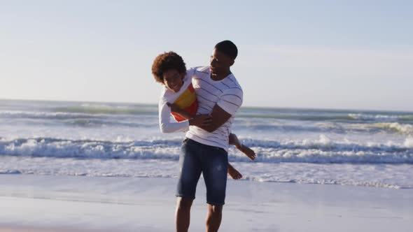 African american father picking up his son and playing at the beach