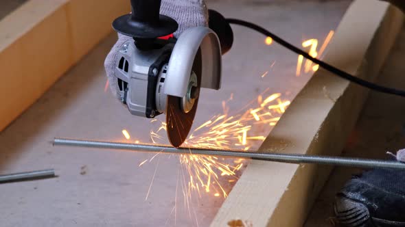 A builder's hands in work gloves cut a metal hairpin with an angle grinder electric tool. Preparatio