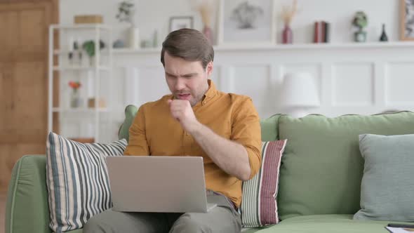 Young Man with Laptop Coughing on Sofa