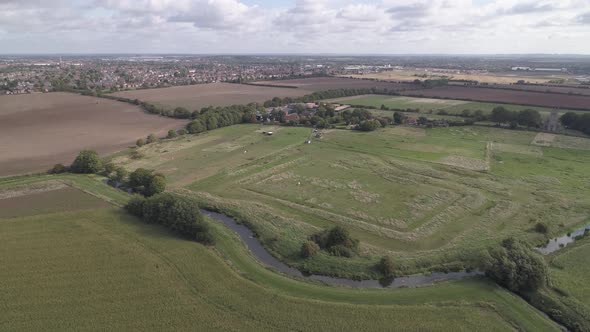 Aerial pan shot of fields and farms with a river cutting through them.