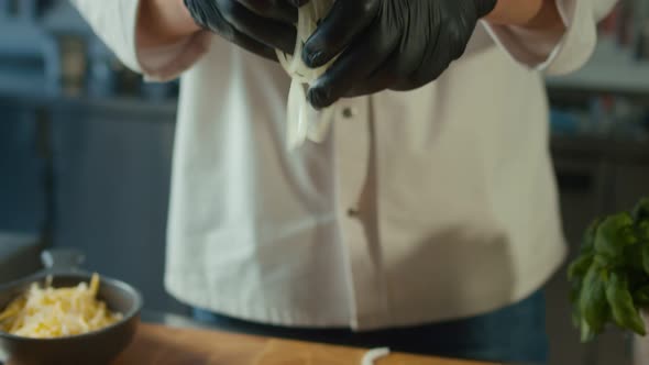 Cook in Gloves Throws Rings of Onion on Wooden Board