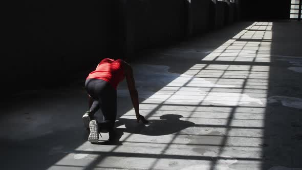 African american man kneeling starting a run in an empty building