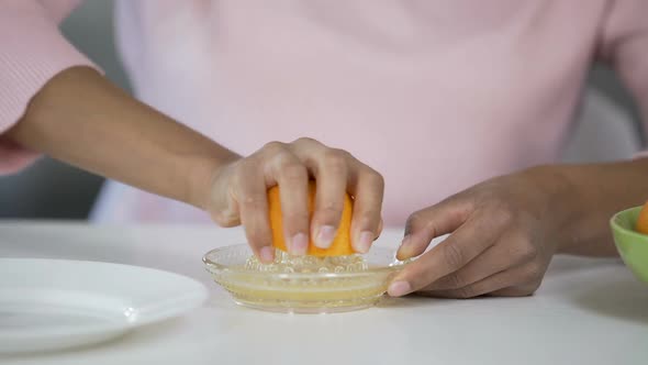 Woman Juicing out Orange with Handheld Juicer, Taking Care of Health, Nutrition