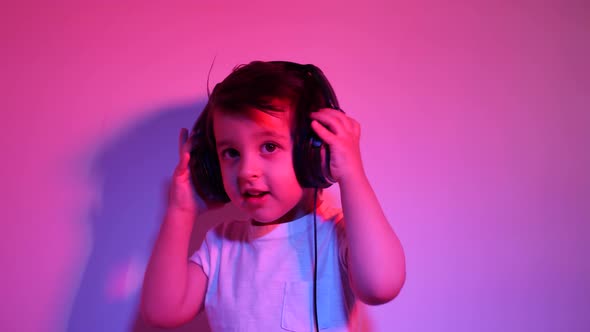 Boy in a White t Shirt Is Listening To Music on Headphones Against a Wall