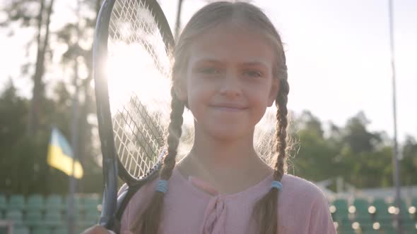 Portrait Cute Little Smiling Girl with Pigtails and a Tennis Racket on Her Shoulder