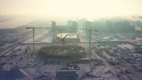 Large Cranes at Snowy Construction Site of Sports Stadium