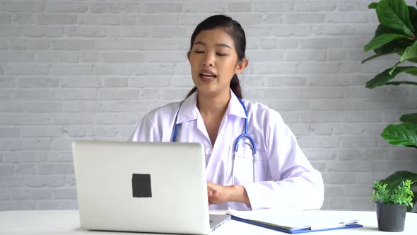 Online Video Conference Chat with Asian Female Doctor and Patient While Discussing on Laptop