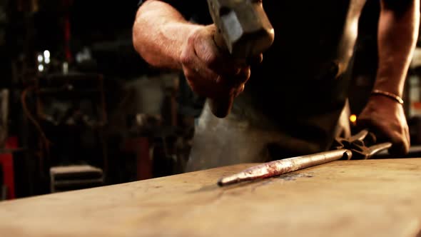 Mid-section of blacksmith working on a iron rod