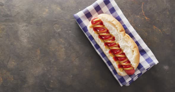 Video of hot dog with mustard and ketchup on a black surface