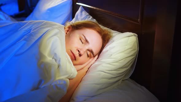 a Woman with Red Hair Sleeps on Her Side in Bed and Sees Quiet Dreams