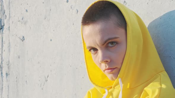 Serious Confident Strong Young Woman with Short Hair in Yellow Hoodie Looking at Camera