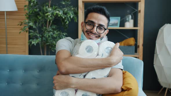 Portrait of Happy Arab Guy Hugging Pack of Toilet Paper and Smiling at Home