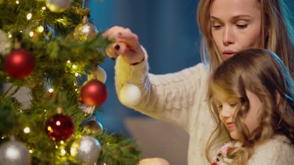 Mother Helping Her Daughters Decorating Christmas Tree